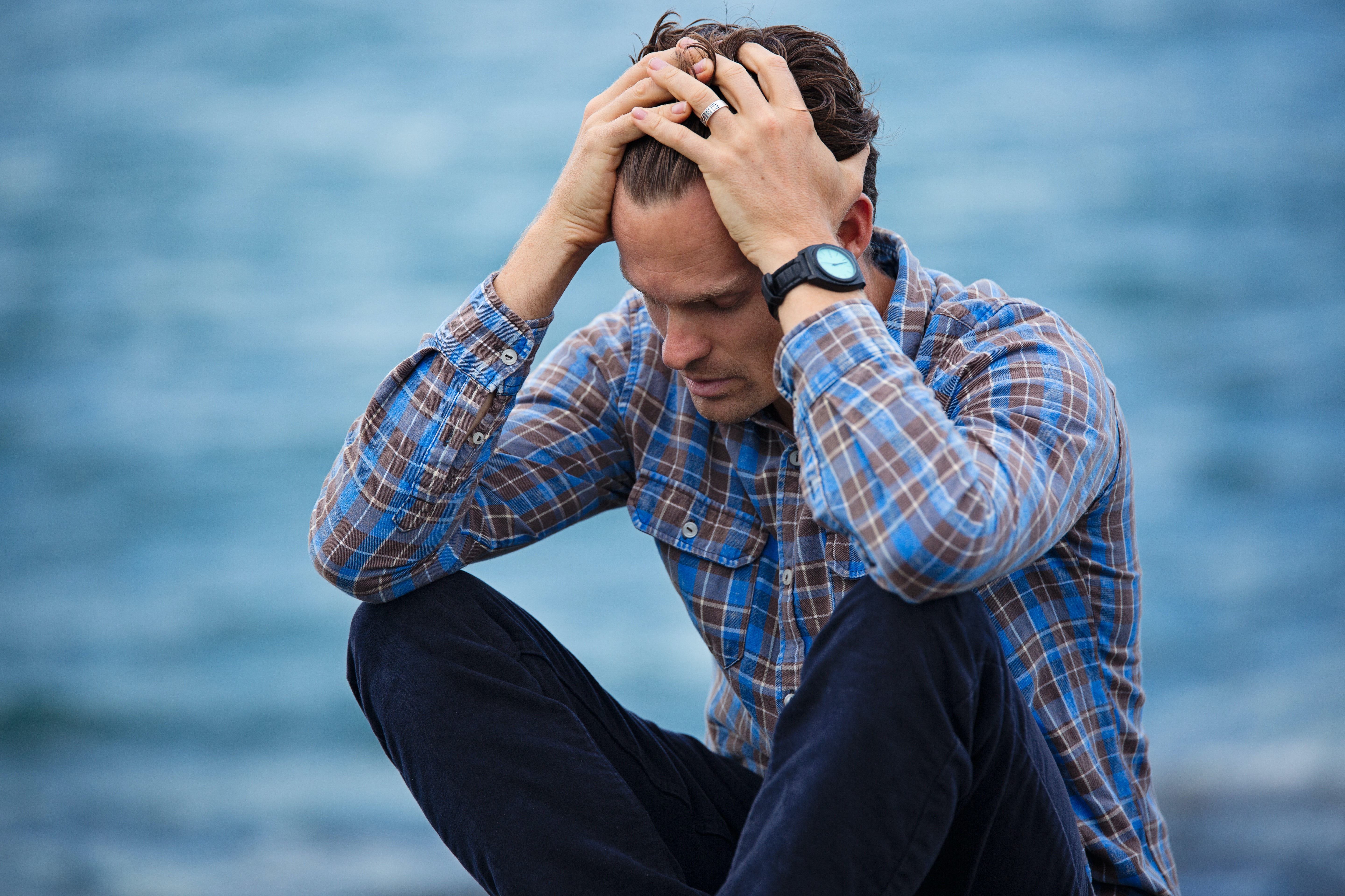 A stressed out man holding his head in his hands